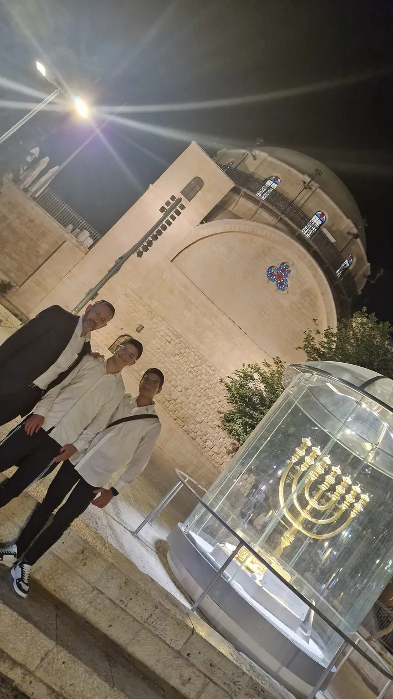 שני תלמידים ומלווה ליד מנורה בתצוגת זכוכית בירושלים - סיור לילי בעיר העתיקה
