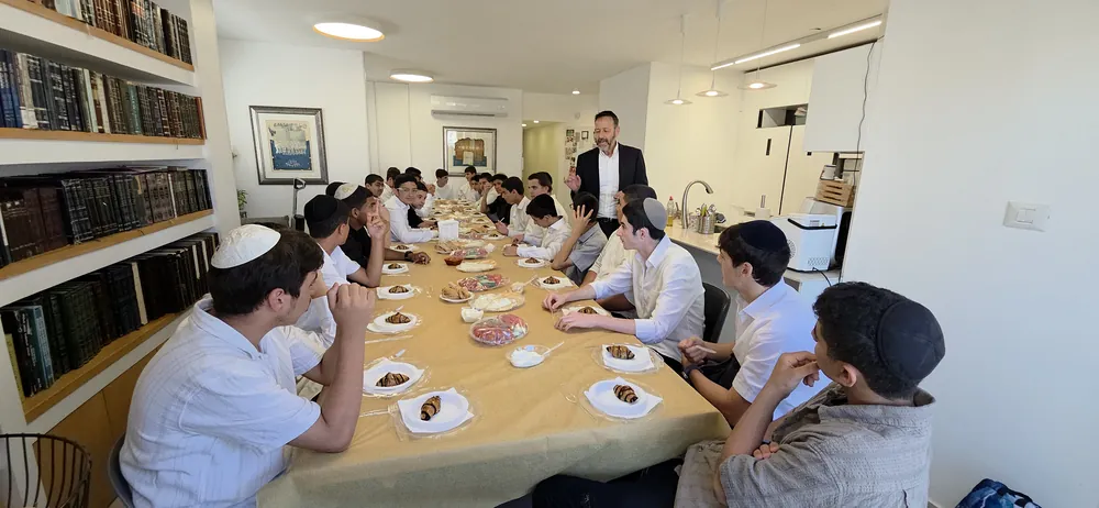 מורה מסביר לתלמידים ליד ספריית ספרים - בוקר ערכי לשיעור א׳ בראש חודש תמוז