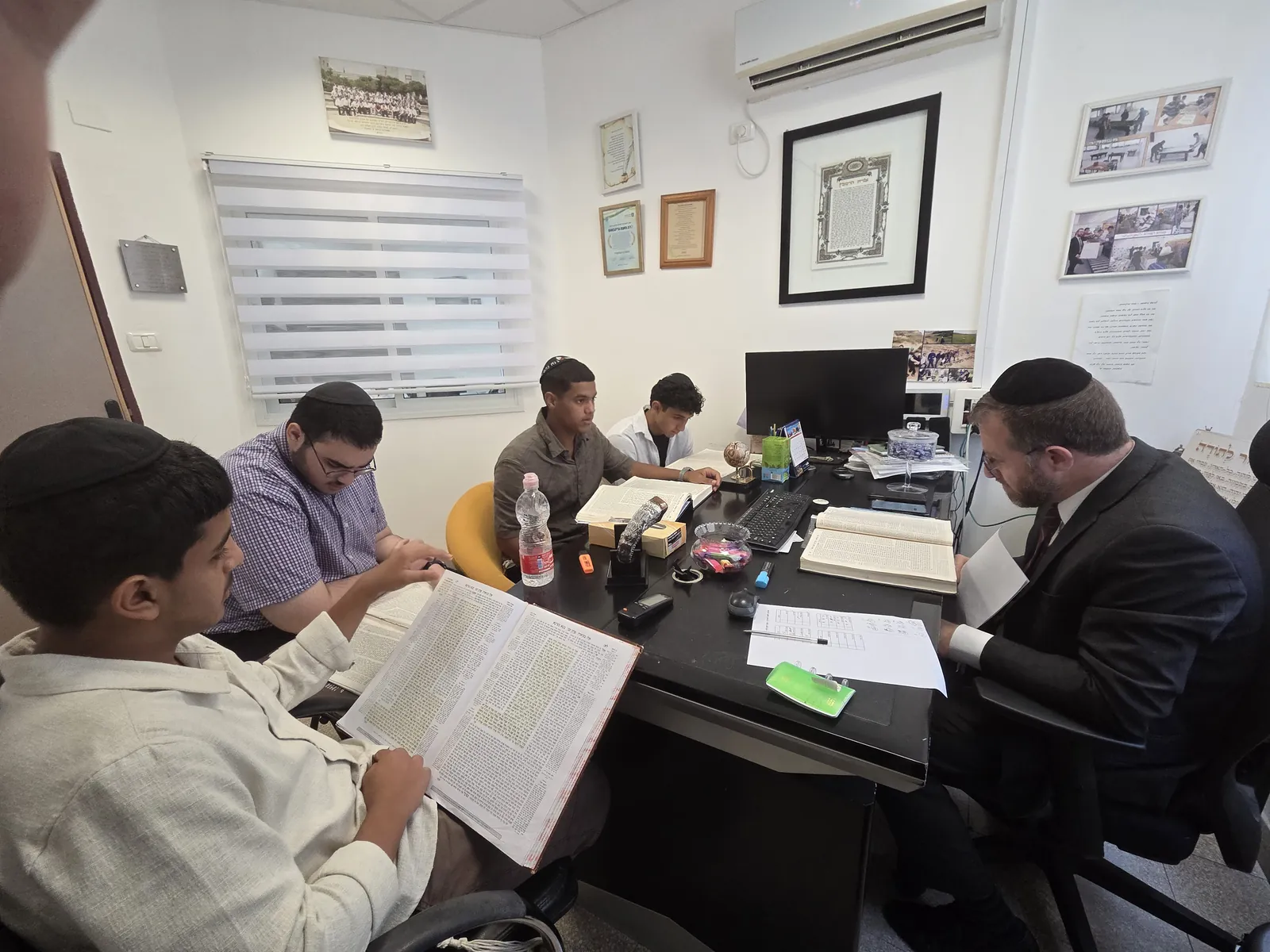 מבט מהצד על תלמידים ורב הלומדים סביב שולחן - מבחן אצל ראש הישיבה
