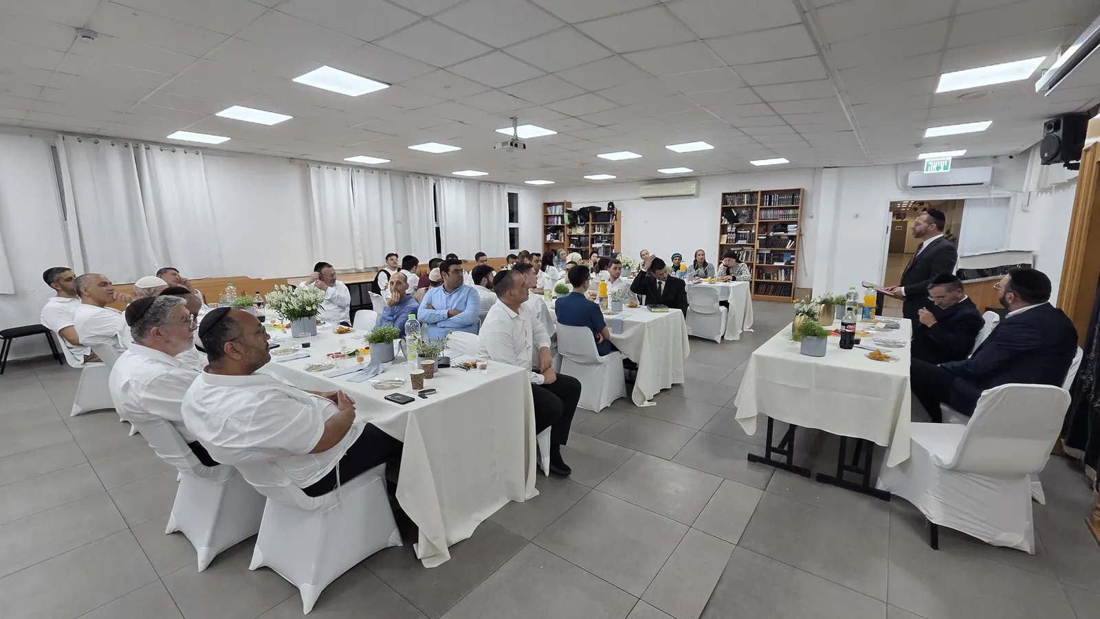 אולם הסעודה והדובר ליד הדוכן במבט רחב - מסיבת סיום לשיעור ד׳
