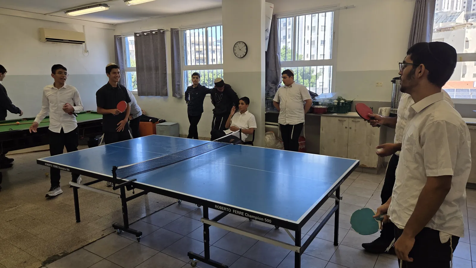 שחקנים וצופים סביב שולחן טניס - טורניר קיץ בטניס שולחן ובביליארד