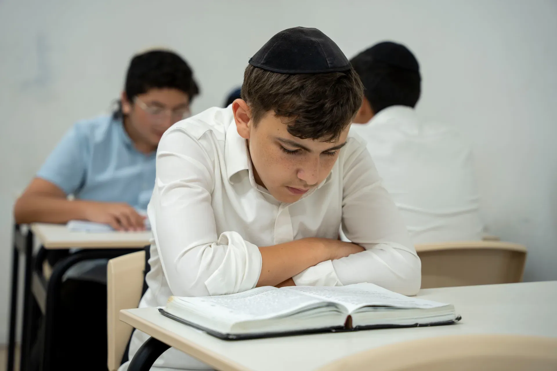 תלמיד לומד בגמרא ליד השולחן בכיתה